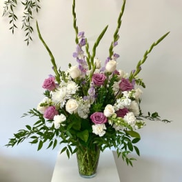 Tall bouquet of purple and white roses in a clear glass vase