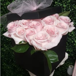 Pink roses arranged in a black box with a sheer ribbon bow