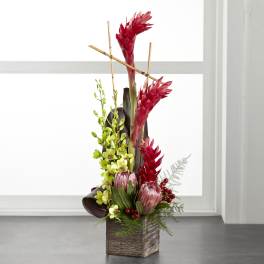 Tall tropical arrangement with red blooms in a wooden cube vase