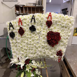 Large floral tribute board with white chrysanthemums, red roses, and lilies