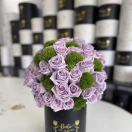 Lavender roses arranged with green pom-pom accents in a black hat box