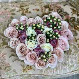 Heart-shaped bouquet of pale pink and white roses with small berry sprigs