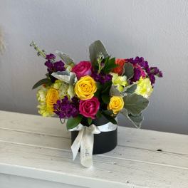 Colorful rose bouquet in a black hat box with a ribbon