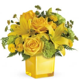 Yellow roses and lilies in a square glass vase