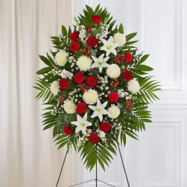 Standing floral spray with red and white flowers on a tripod easel
