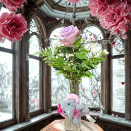 Pink rose in a glass vase with a small plush elephant