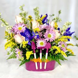 Mixed bouquet in a pink container with small garden tools