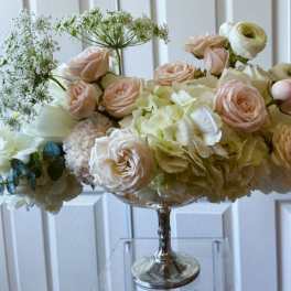 Blush roses and cream hydrangeas in a silver pedestal vase