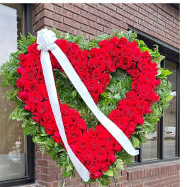 Heart-shaped red rose standing spray with a white ribbon