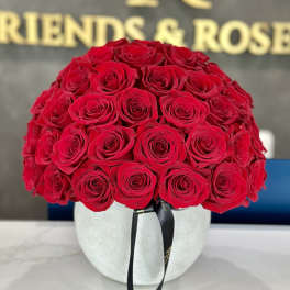 Round bouquet of red roses in a white hatbox with a black ribbon