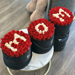 Three round boxes of red and white roses arranged on tables