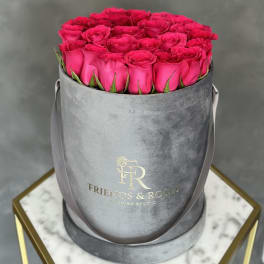 Hot pink roses arranged in a gray round hat box