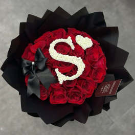 Red rose bouquet with a white floral letter S and black wrapping