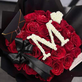 Bouquet of red roses with white lettering and a black ribbon