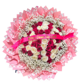 Round bouquet of pink and white roses with pink wrapping and ribbon