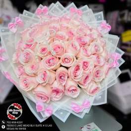 Round bouquet of light pink roses with crystal centers wrapped in white paper and pink bows