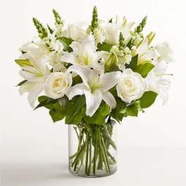 White lilies and roses arranged in a clear glass vase