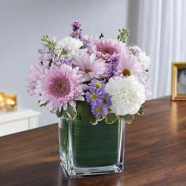 Pink and white flowers arranged in a clear square vase