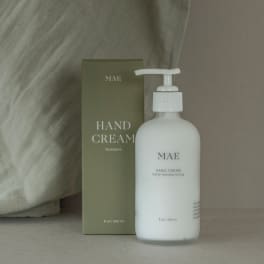 Bottle of hand cream beside its olive-green box