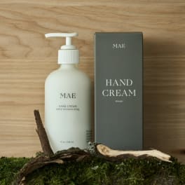 Hand cream bottle beside its box on a wood surface with moss and bark