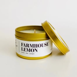 Gold tin candle labeled Farmhouse Lemon with lid beside it