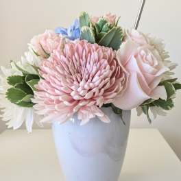 Pastel arrangement of pink chrysanthemum, rose, and white flowers in a light blue vase