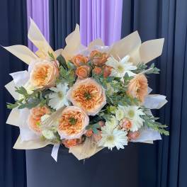 Peach roses and white daisies in a wrapped bouquet