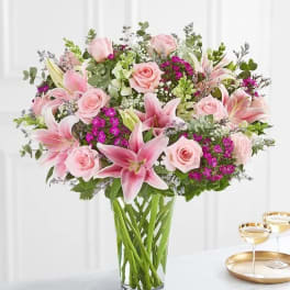 Pink lilies and roses arranged in a clear glass vase