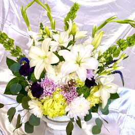 White lilies and mixed flowers arranged in a white vase