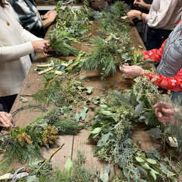 People arranging greenery bundles on a wooden table