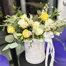 Yellow and white roses arranged in a white hat box with a ribbon