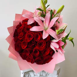 Bouquet of red roses and pink lilies wrapped in pink paper
