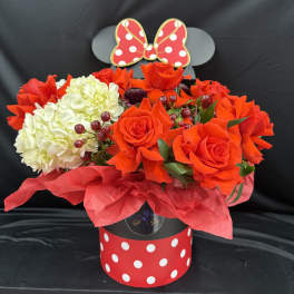 Red roses and white hydrangeas in a polka-dot gift box with a bow topper