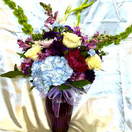 Mixed bouquet in a purple vase with blue hydrangea and yellow roses