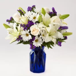 White lilies, daisies, and roses in a blue vase