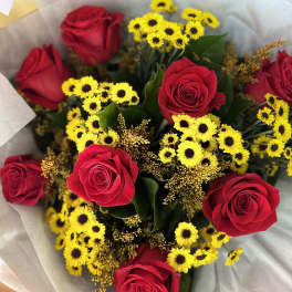 Bouquet of red roses and small yellow daisies wrapped in pale paper
