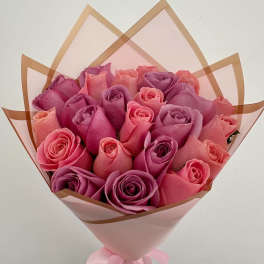 Bouquet of pink and purple roses wrapped in pink paper with a ribbon