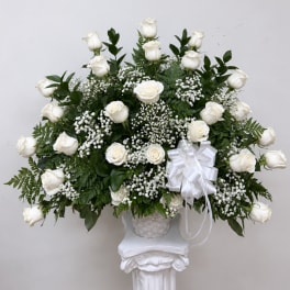 White rose arrangement in a basket with a white ribbon bow