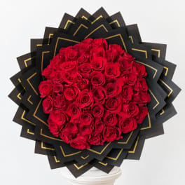 Large bouquet of red roses wrapped in black paper with gold trim