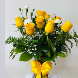 Yellow roses in a glass vase with a yellow ribbon