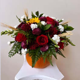 Mixed bouquet in a pumpkin vase with red roses and white blooms