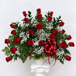 Red roses in a white basket with a red ribbon bow