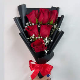 Bouquet of red roses wrapped in black paper with a red ribbon