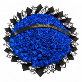 Blue rose bouquet with black-and-white patterned wrap and a birthday ribbon