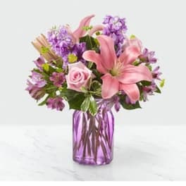 Pink lilies and roses in a purple glass vase