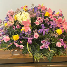 Large pink, purple, and yellow floral spray on a casket