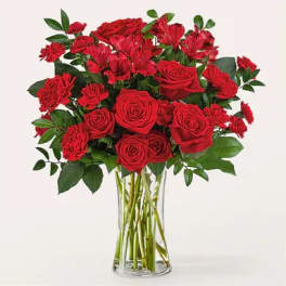 Red roses and carnations in a clear glass vase