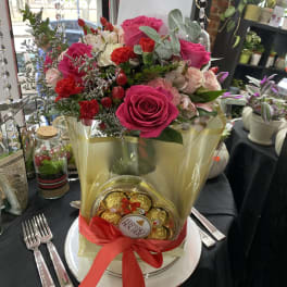 Pink rose bouquet with chocolates in a gold wrap and red ribbon