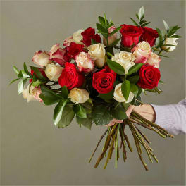 Handheld bouquet of red and white roses with greenery