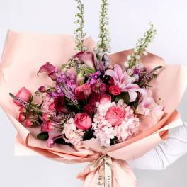 Pink bouquet with roses, lilies, and hydrangeas wrapped in peach paper